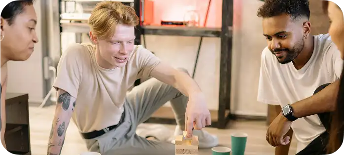 Een groepje jongeren zit op de grond en speelt een bordspel met een houten toren.