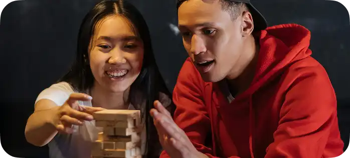 Een jongen en een meisje reageren emotioneel op het instorten van de houten Jenga-toren tijdens het spel.