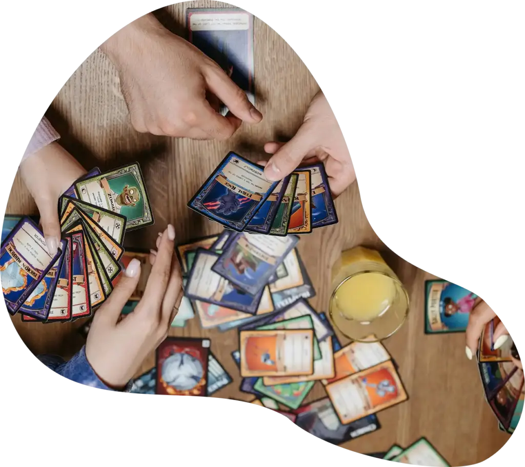 Een bovenaanzicht van mensen met kaarten aan een houten tafel tijdens een bordspel.